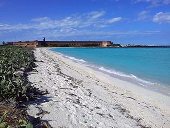 Soft sand beach, blue-green ocean, and Fort Jefferson in the distance