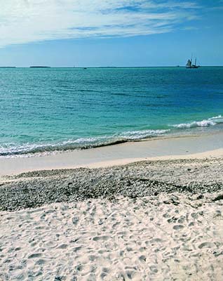 View of sandy beach, sailboats and calm, turquoise ocean