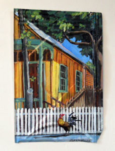 Rick Worth painting on metal roofing shingle of a rooster and wooden house