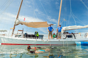 Snorkelers swimming away from the anchored schooner in the calm seas of the Key West backcountry islands